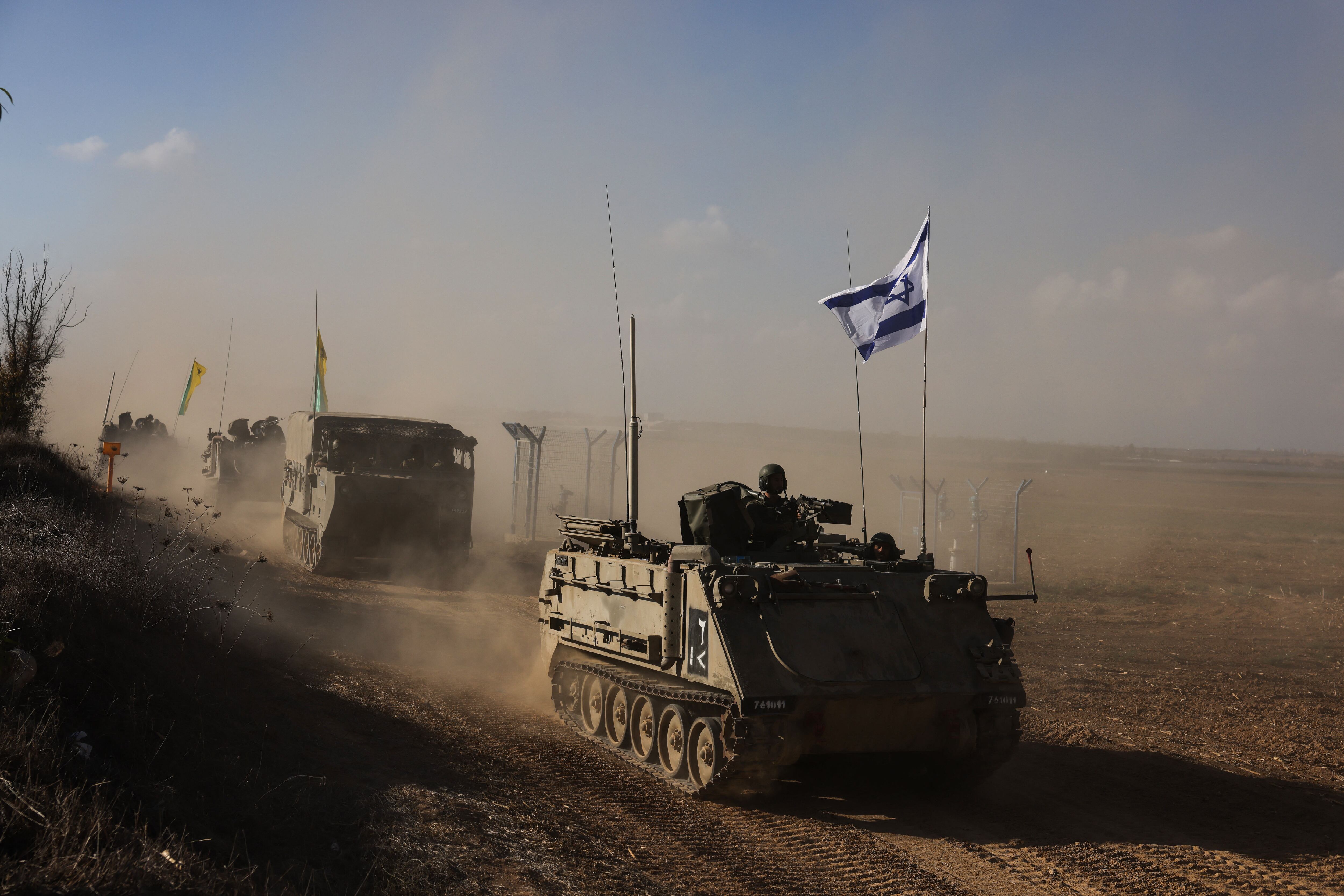 A convoy of Israeli military vehicles drives along a road in an undisclosed location on the border with the Gaza Strip on October 15, 2023. (Photo by Menahem KAHANA/AFP).