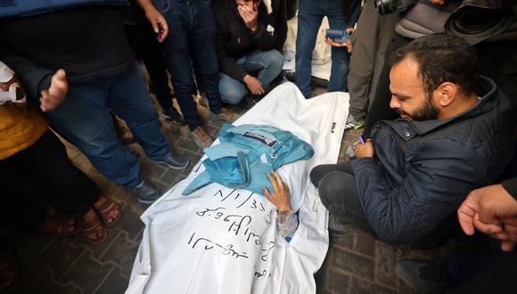 Compañeros periodistas lloran ante el cuerpo de Hamza Wael Dahdouh, periodista de la cadena de televisión Al Jazeera, que murió en un ataque aéreo israelí durante su funeral en Rafah, en la Franja de Gaza, el 7 de enero de 2024. (Foto de AFP)