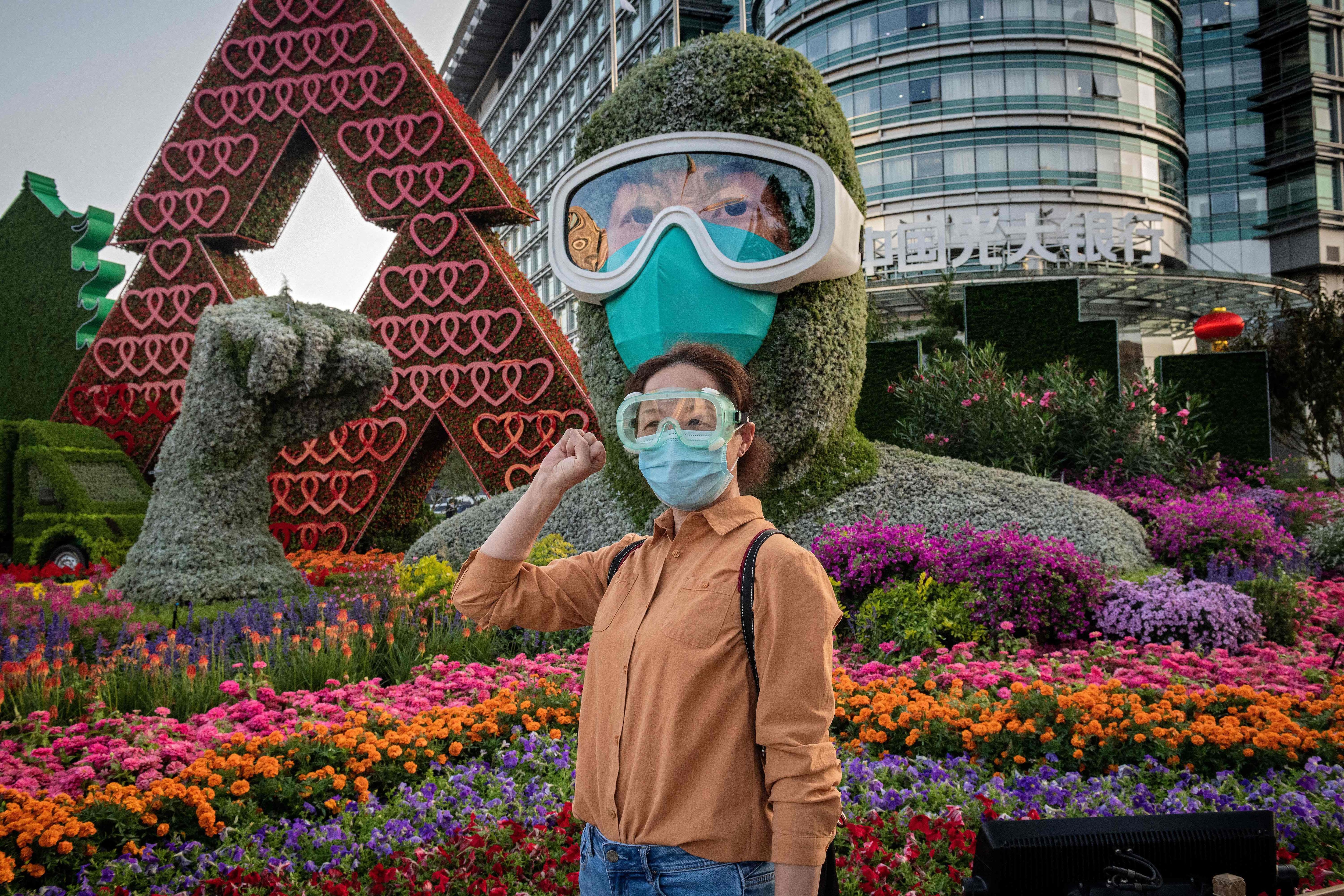 Una mujer posa frente a una exhibición de flores dedicada a los trabajadores de la salud de primera línea durante la pandemia de Covid-19 en celebración del próximo Día Nacional de la República Popular de China, en Beijing. (Foto: NICOLAS ASFOURI / AFP)