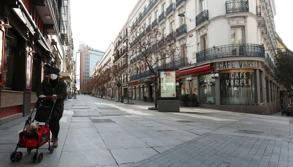 Una mujer con una máscara facial protectora camina en una calle vacía de Madrid durante el primer día del estado de alarma en España por el coronavirus.
(REUTERS/Sergio Perez).