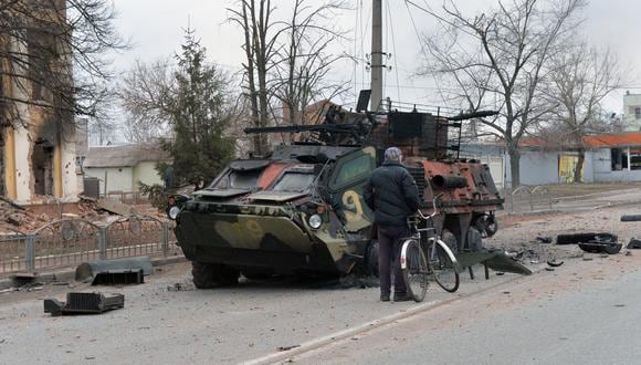 Un hombre mira un vehículo blindado de transporte de personal (APC) ucraniano BTR-4 destruido como resultado de una pelea no lejos del centro de la ciudad ucraniana de Kharkiv, ubicada a unos 50 km de la frontera entre Ucrania y Rusia. (Foto: Sergey BOBOK / AFP).
