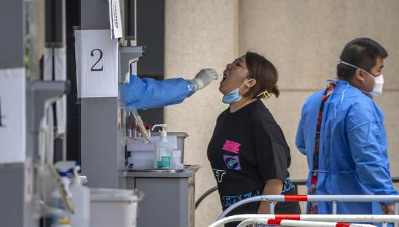 Un trabajador toma una muestra de la garganta de una mujer en un sitio de pruebas de coronavirus en el tercer día de pruebas masivas para millones de residentes en el distrito de Chaoyang en Beijing.