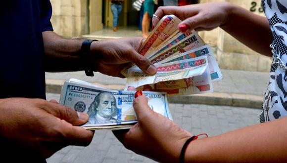 Un hombre y una mujer cambian billetes de CUC y dólares en una calle de La Habana, Cuba, el 10 de diciembre de 2019. (YAMIL LAGE / AFP).