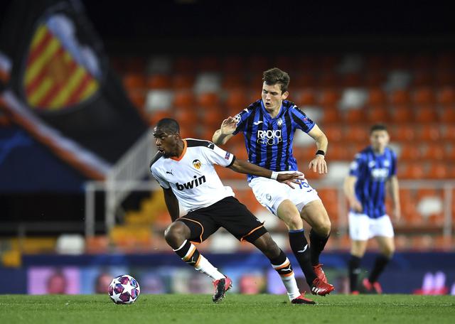 Valencia's Geoffrey Kondogbia, left, duels for the ball with Atalanta's Marten de Roon during the Champions League round of 16 second leg soccer match between Valencia and Atalanta in Valencia, Spain, Tuesday March 10, 2020. The match is being in an empty stadium because of the coronavirus outbreak. (UEFA via AP)
