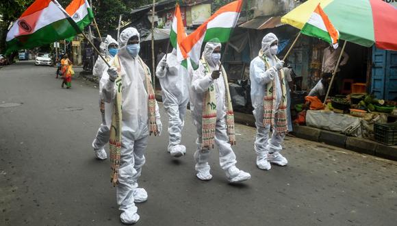 Guerreros del coronavirus COVID-19 de primera línea, como trabajadores de la salud, conductores de ambulancias, trabajadores de crematorios, vestidos con equipos de protección personal, sostienen banderas de la India como parte de las celebraciones del Día de la Independencia en Calcuta el 15 de agosto de 2020. (Foto: Dibyangshu SARKAR / AFP).