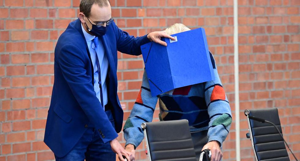 El acusado Josef Schutz esconde su rostro detrás de una carpeta cuando llega para su juicio en Brandenburg an der Havel, en el noreste de Alemania, el 7 de octubre de 2021. (TOBIAS SCHWARZ / AFP).