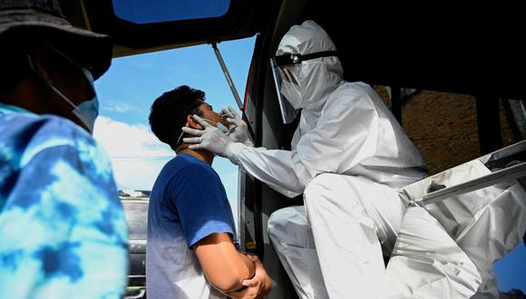 Un trabajador de salud se somete a una prueba de muestra de hisopo para el coronavirus durante las restricciones de bloqueo en un puesto de control en Lambaro, provincia de Aceh (Indonesia), el 16 de julio de 2021. (Foto de CHAIDEER MAHYUDDIN / AFP).
