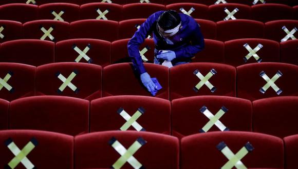 Imagen referencial. Trabajador desinfecta una sala de cine entre funciones. Sillas con X marcan las butacas que deben estar libres para mantener el distanciamiento social. (Foto: Mast Irham/EFE)