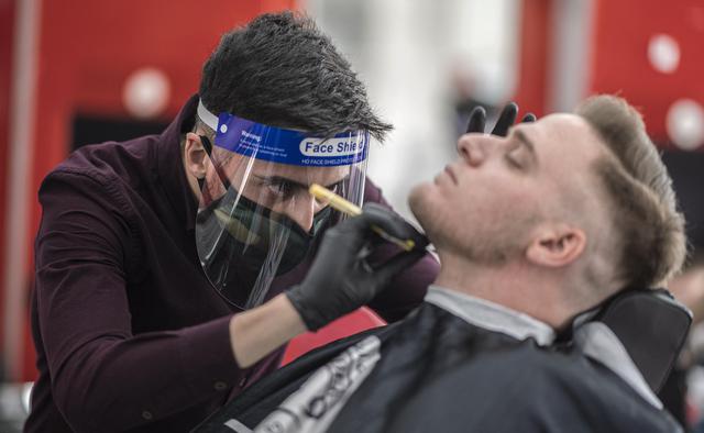 Un peluquero, con guantes, una mascarilla protectora y un protector facial, afeita a un cliente en Viena, Austria,  tras levantarse las medidas que dictó el Gobierno para frenar el coronavirus. (Foto: EFE / EPA / CHRISTIAN BRUNA).