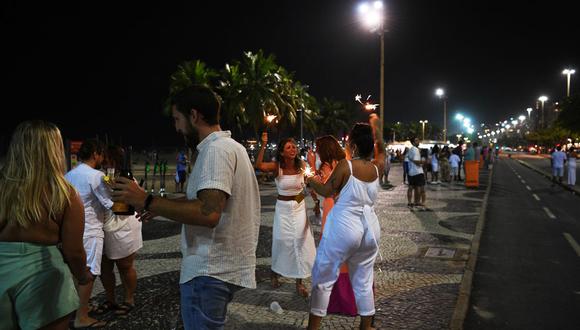Un grupo de personas celebra la víspera de Año Nuevo en la playa de Copacabana, Río de Janeiro, Brasil. (Foto: CARL DE SOUZA / AFP).