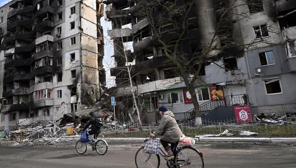 La gente pasa en bicicleta frente a los edificios destruidos en la ciudad de Borodianka, al noroeste de Kiev, el 4 de abril de 2022. La UE dijo el 4 de abril de 2022 que está discutiendo con urgencia una nueva ronda de sanciones contra Rusia, ya que condenó las "atrocidades" denunciadas en ucraniano. ciudades que han sido ocupadas por las tropas de Moscú. Rusia invadió Ucrania el 24 de febrero de 2022. (Serguéi SUPINSKY / AFP)