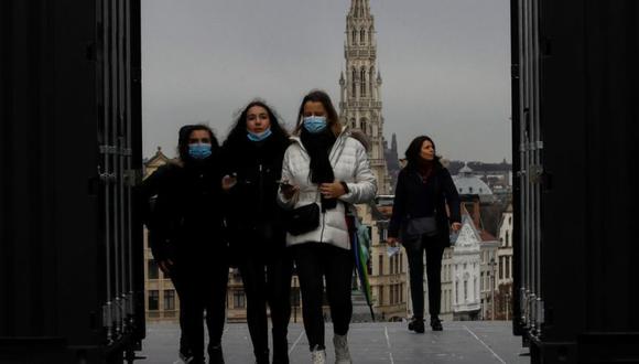 Un grupo de peatones, algunos de ellos con mascarillas protectoras, pasean por la ciudad mientras miembros del gobierno belga se reúnen para imponer nuevas resistencias para frenar la propagación de la pandemia de coronavirus, en Bruselas, Bélgica. (Foto: EFE / EPA / OLIVIER HOSLET).