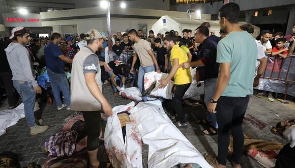 Personas reunidas alrededor de los cuerpos de palestinos muertos en un ataque aéreo de Israel contra el hospital árabe Ahli en el centro de Gaza. (Foto de Dawood NEMER / AFP).