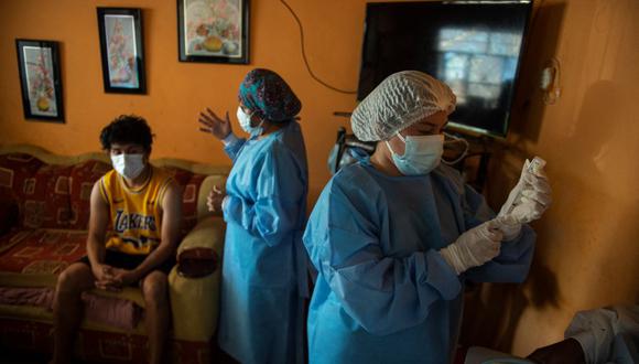 Trabajadoras de salud se preparan para inocular a un hombre con una dosis de la vacuna AstraZeneca / Oxford contra el coronavirus COVID-19 en el distrito de Buenos Aires, provincia de Morropón, en Piura, norte del Perú. (Ernesto BENAVIDES / AFP).