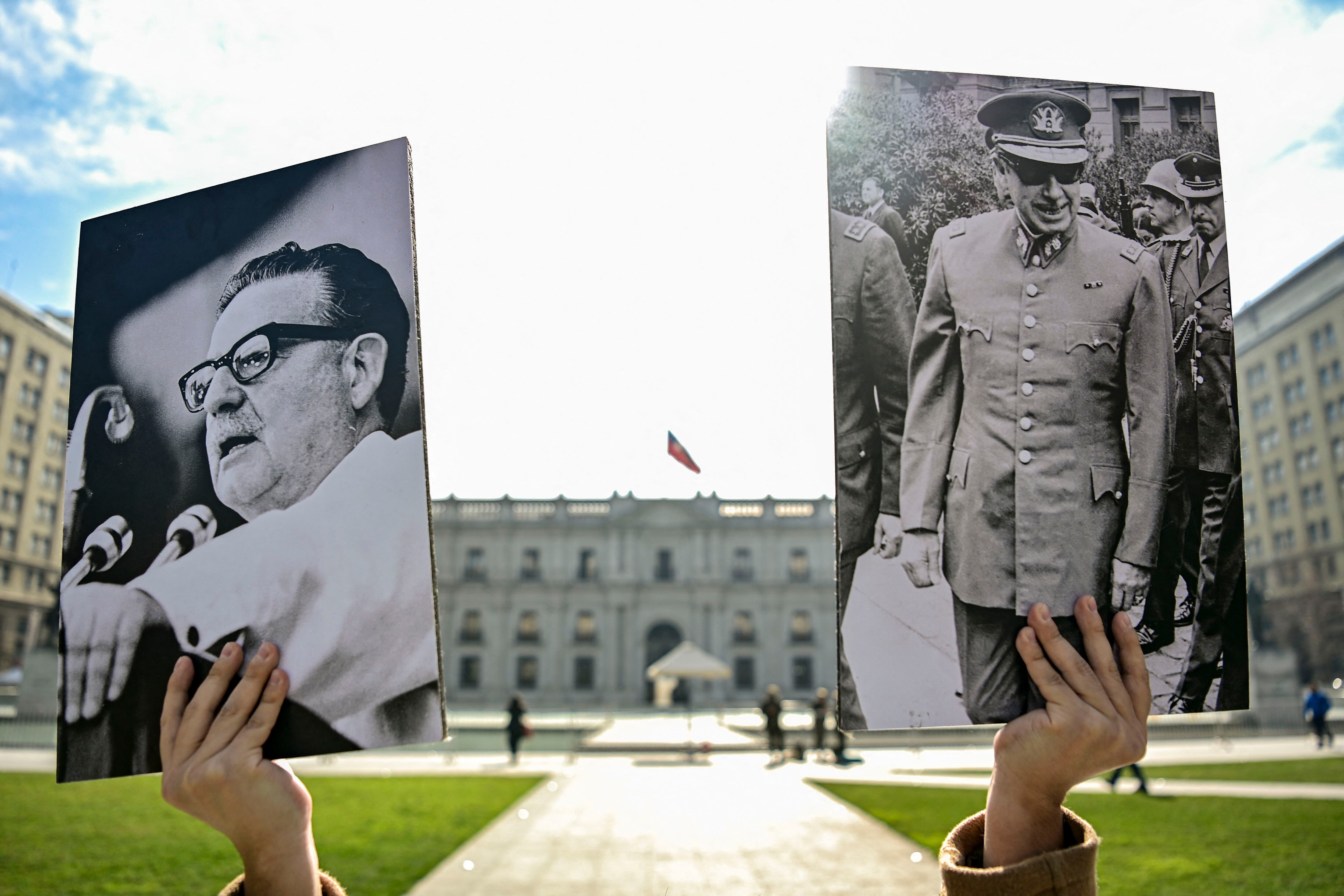 A young man holds a photograph of the late Chilean president Salvador Allende and Chilean dictator Augusto Pinochet outside the La Moneda Presidential Palace, on August 1, 2023. (MARTIN BERNETTI / AFP).