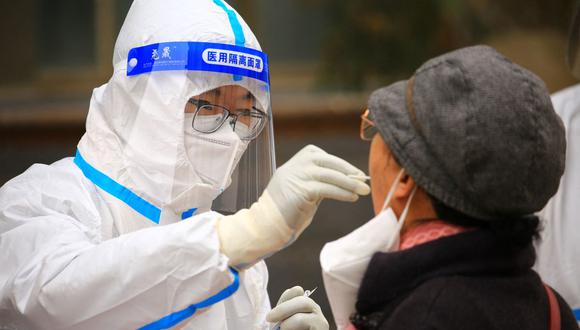 Un trabajador de la salud toma una muestra de hisopo de una residente para hacerle la prueba del coronavirus Covid-19 en Jiayuguan, en la provincia noroccidental china de Gansu, el 24 de noviembre de 2022. (STR / AFP).
