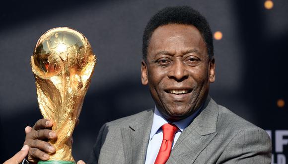 La leyenda del fútbol brasileño Pelé posa con el trofeo de la Copa Mundial de la FIFA el 9 de marzo de 2014 en París. (AFP PHOTO/FRANCK FIFE).