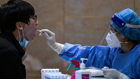 Un trabajador de la salud toma una muestra de un hisopo de un periodista para hacerle la prueba del coronavirus Covid-19, la noche anterior al 14º Comité de la Conferencia Consultiva Política del Pueblo Chino (CCPPCh) en Beijing el 3 de marzo de 2023 (Foto: NOEL CELIS / AFP)
