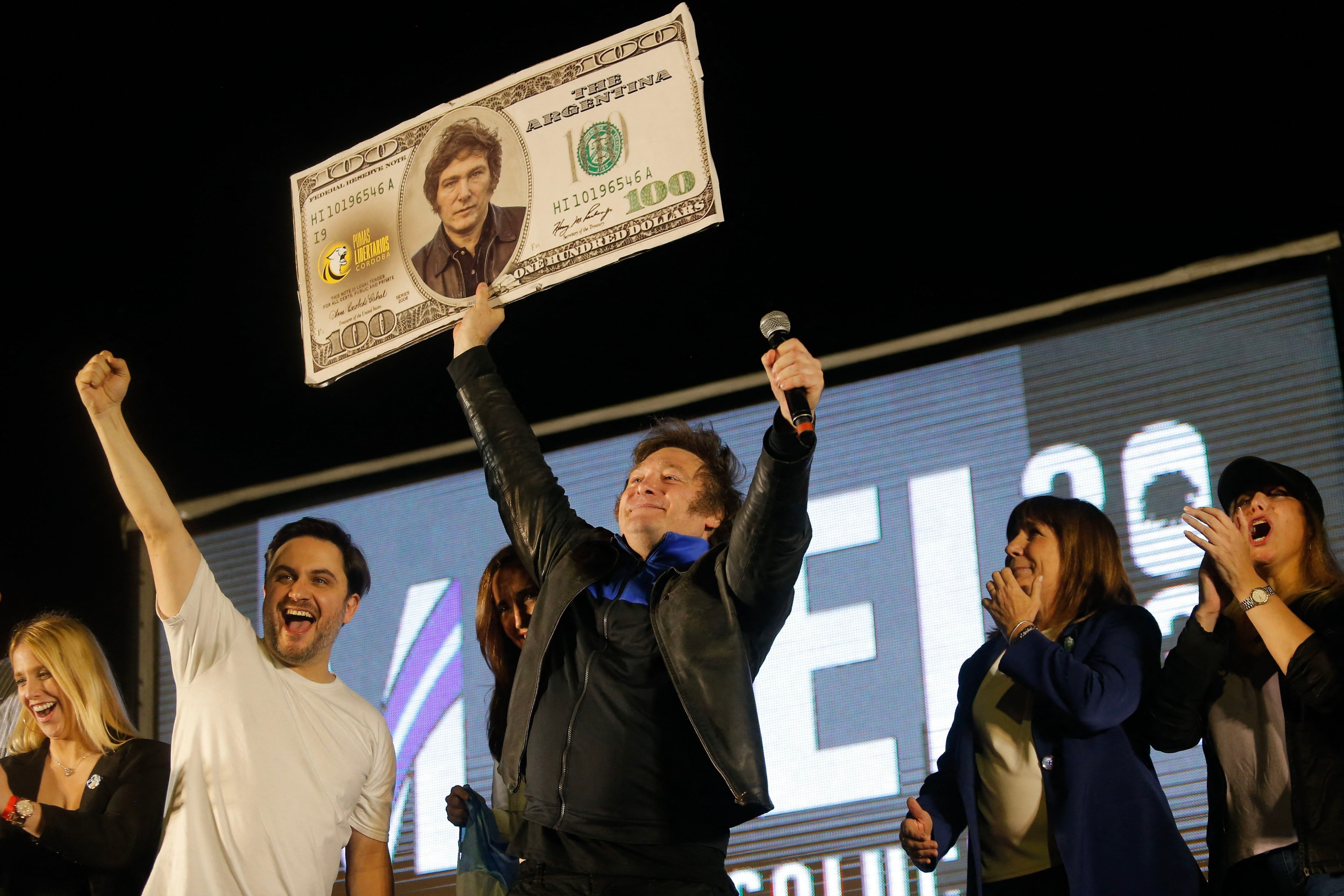 Javier Milei holds up a fake US$100 bill with his image during the end of his electoral campaign in Córdoba, Argentina, on November 16, 2023. (Photo by DIEGO LIMA/AFP).