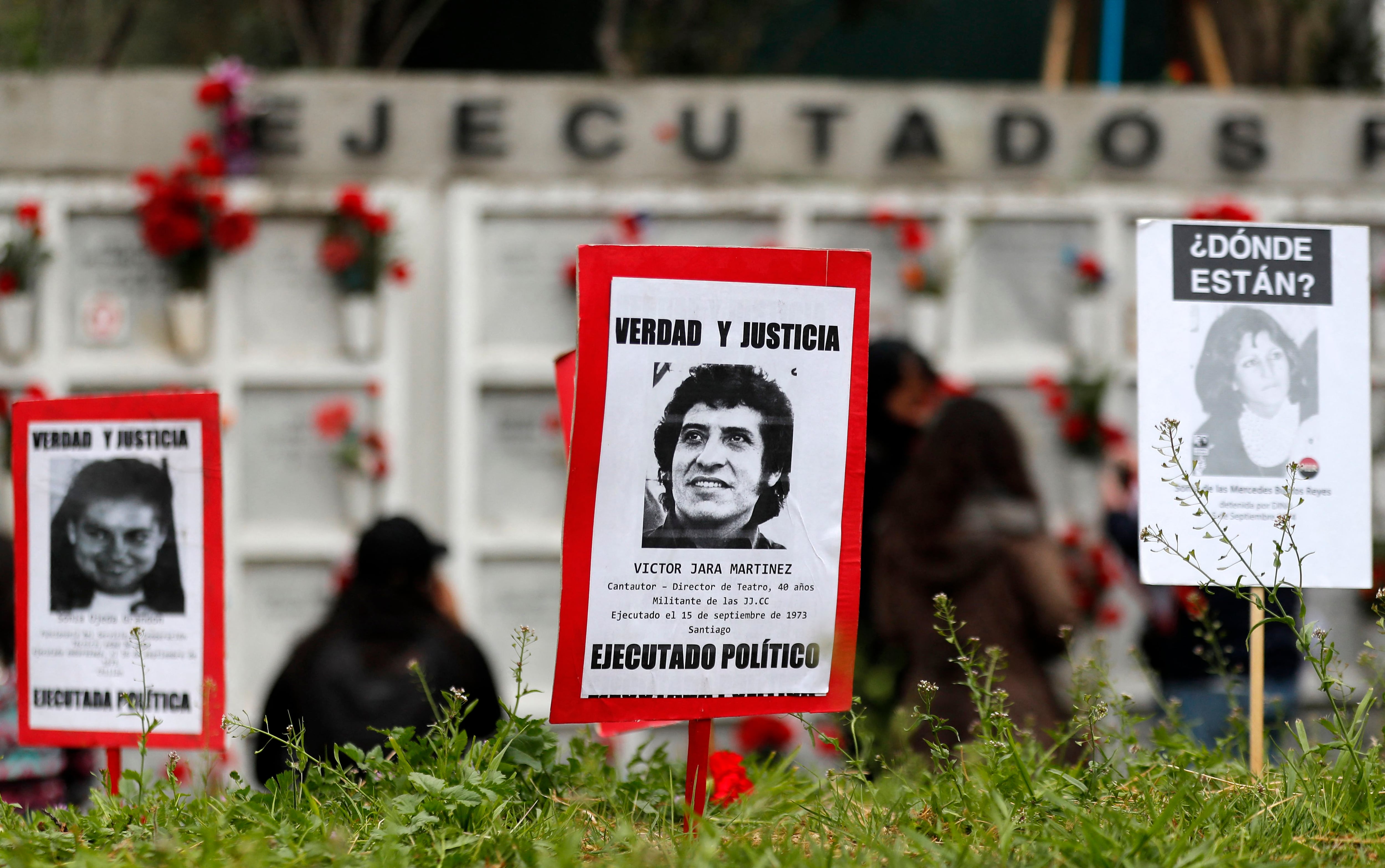 A poster with a photo of teacher and singer Víctor Jara, who was tortured and shot to death during the Chilean dictatorship, is seen as people demonstrate at the General Cemetery.  (Photo by Javier TORRES/AFP).