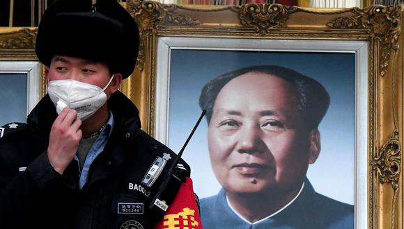 Un guardia de seguridad que usa una mascarilla se para junto a un retrato del difunto líder comunista chino Mao Zedong en un centro comercial en Beijing el 27 de enero de 2020. (Foto de Noel Celis / AFP).