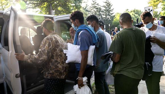 Migrantes de Venezuela esperan ser transportados a una iglesia local por voluntarios después de ser dejados frente a la residencia de la vicepresidenta de EE. UU. Kamala Harris, en el Observatorio Naval en Washington, DC. (Foto de Stefani Reynolds / AFP)