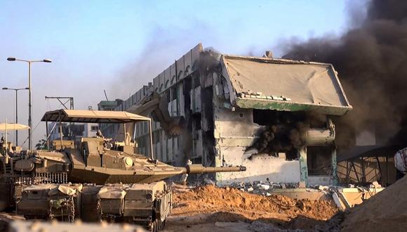 Tanques israelíes rodando mientras una topadora del ejército derriba un edificio en llamas dentro de la Franja de Gaza, el 11 de noviembre de 2023. (Foto de Armada israelí / AFP)