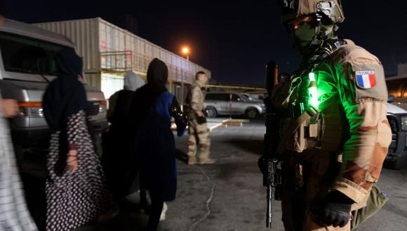 Un soldado francés mira a la gente que camina para abordar un avión de transporte militar A400M Atlas en el aeropuerto de Kabul, Afganistán. (ETAT MAJOR DES ARMEES / AFP).