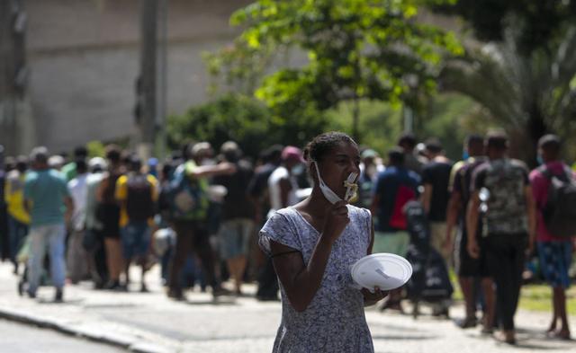 Personas sin hogar reciben almuerzo en el centro de Sao Paulo, Brasil, el 23 de marzo de 2021, en medio de la pandemis de coronavirus. (Foto de Miguel SCHINCARIOL / AFP).