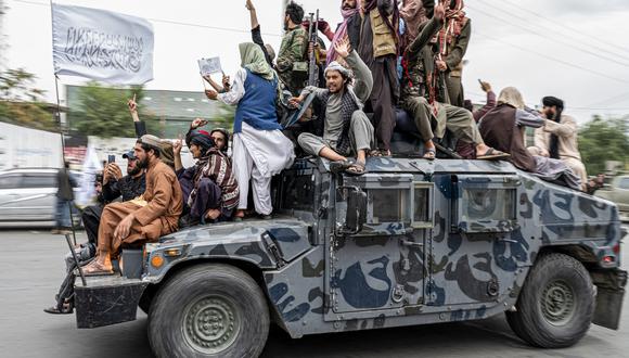 Los combatientes talibanes sostienen armas mientras viajan en un humvee para celebrar el día de su victoria cerca de la embajada de EE. UU. en Kabul el 15 de agosto de 2022.  (Foto de Wakil KOHSAR / AFP)