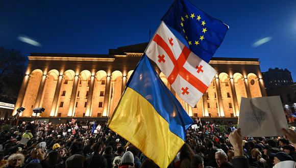 Los manifestantes ondean las banderas georgiana, ucraniana y europea durante una manifestación frente al Parlamento de Georgia en Tiflis el 8 de marzo de 2023. (Foto de Vano SHLAMOV / AFP)