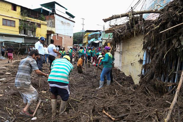 Residents help rescue workers clear mud from destroyed homes as they search for victims of a landslide in Tejarías, Venezuela's Aragua state.  (Yuri Cortes / AFP).