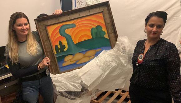 Las autoridades sostienen la pintura de la artista Tarsila do Amaral titulada "Sol Poente" después de que fuera incautada durante una operación policial en Río de Janeiro, Brasil. (Foto: Reuters)