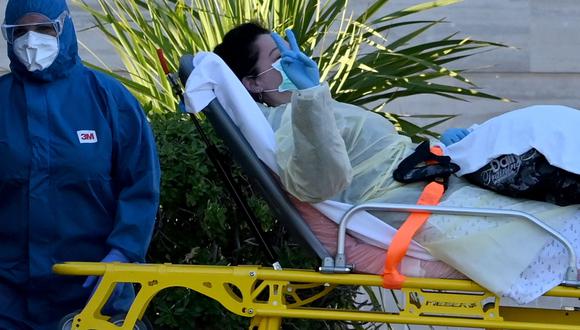 Una paciente muestra el signo de la victoria mientras es llevada en una camilla un hospital temporal de Italia habilitado para pacientes de coronavirus. (AFP / ANDREAS SOLARO).