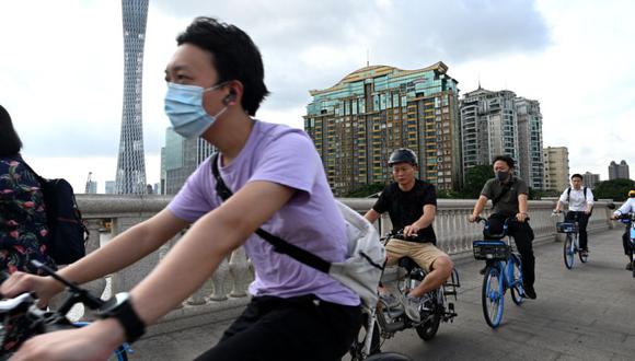 Personas en bicicleta ante la Torre Cantón (izquierda) en Guangzhou, en la provincia sureña de Guangdong, China. (Foto: NOEL CELIS / AFP).