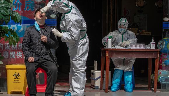 Un trabajador médico con un traje de protección completo hace una prueba a un hombre para detectar síntomas de coronavirus Covid-19 en una calle de Wuhan, China, el 1 de abril de 2020. (EFE / EPA / ROMAN PILIPEY).