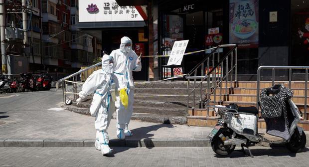 Health workers in protective suits walk along a road in the Chaoyang district of Beijing, China.