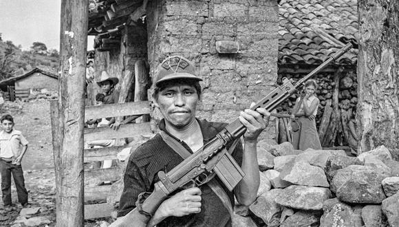 Un miliciano rebelde alza su rifle en un gesto de desafío frente a su casa en el departamento de Chalatenango, ocupado por los rebeldes. El Salvador, 1984. Foto por Scott Wallace.