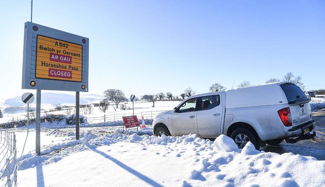 A sign alerts drivers to road closures near Wrexham, north Wales as heavy snowfall blankets the area on December 11, 2017. The heaviest snowfall to hit Britain in four years caused widespread yesterday with roads becoming hazardous and flights grounded following runway closures. / AFP / Paul ELLIS