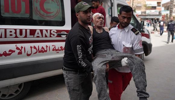 Un paramédico y un hombre transportan a un palestino herido desde una ambulancia al hospital de los Mártires de Al-Aqsa en Deir al-Balah tras el bombardeo israelí en Khan Yunis, en el sur de la Franja de Gaza, el 28 de marzo de 2024. (Foto de AFP)