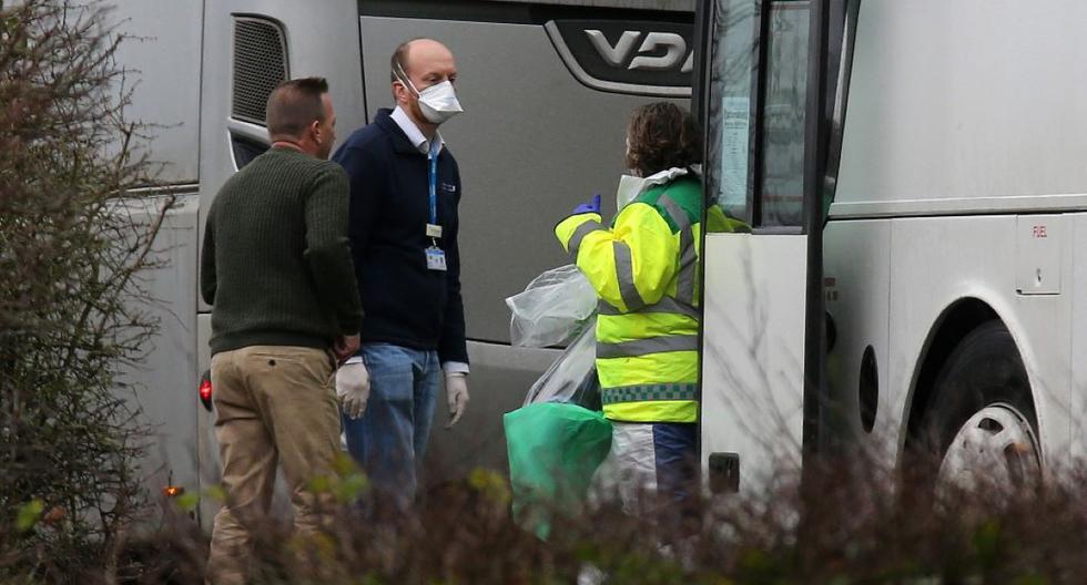 Las personas usan máscaras faciales y guantes protectores mientras se encuentran transportan a un grupo de ciudadanos británicos evacuados de Wuhan en Londres. (AFP)