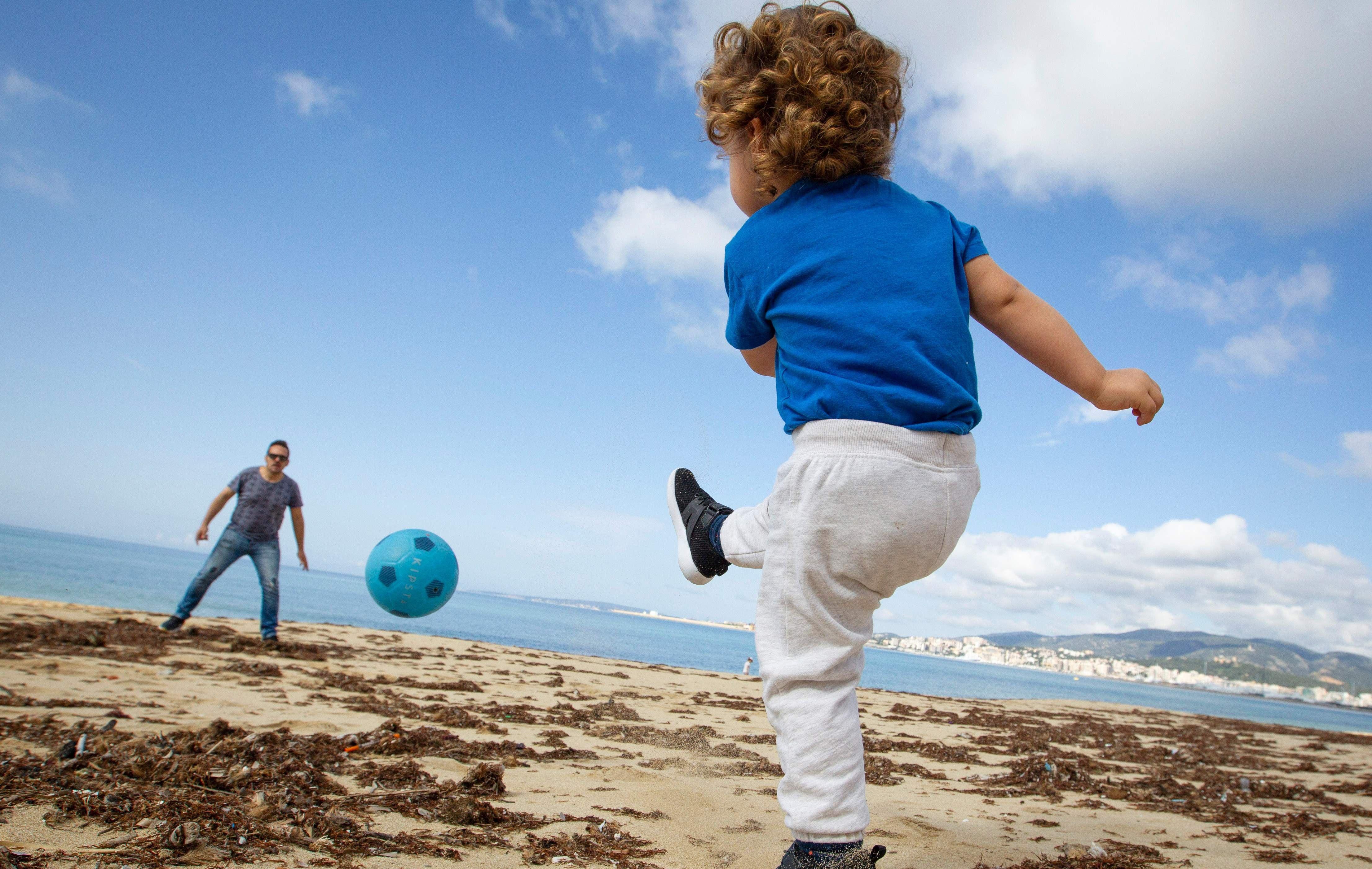 Un niño juega fútbol con su padre en la playa de Can Pere Antoni en Palma de Mallorca. Los menores pudieron salir a la calle en España luego de 6 semanas de cuarentena por coronavirus (AFP / JAIME REINA).
