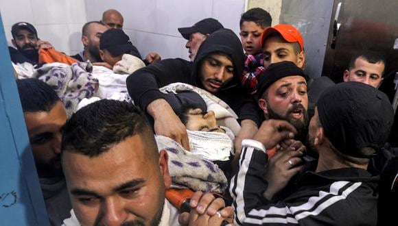 Los dolientes llevan el cuerpo de uno de los palestinos asesinados durante una redada del ejército israelí, en una morgue en el campo de refugiados palestinos de Jenin en la Cisjordania ocupada el 7 de marzo de 2023. (Foto de JAAFAR ASHTIYEH / AFP)