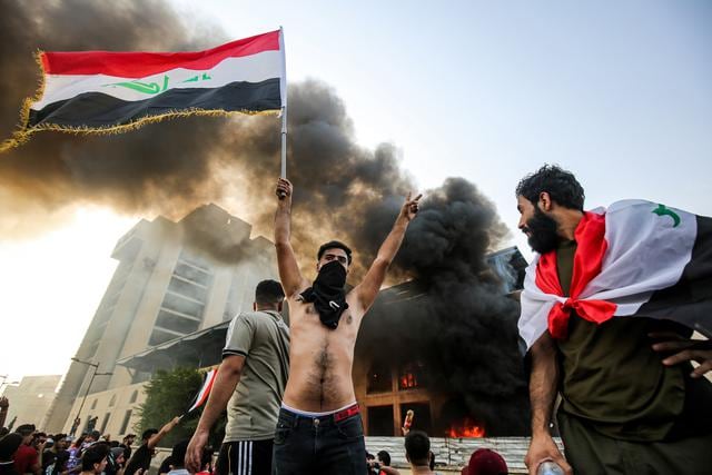 Un hombre enmascarado levanta la bandera iraquí en símbolo de victoria durante una manifestación contra la corrupción estatal. (Foto: AFP)
