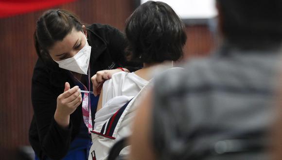 A woman receives a dose of the Pfizer-BioNTech vaccine against COVID-19 at a vaccination center in Santiago, on January 20, 2022. - Chile registered this Thursday a new record of daily infections, with 12,500 new infected, the highest number in the entire pandemic, in one of the countries with the highest percentage of its population vaccinated and that this Thursday began to apply the fourth dose to health personnel. (Photo by JAVIER TORRES / AFP)