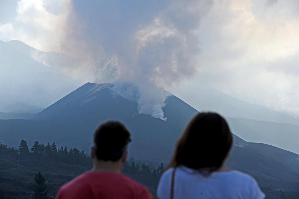 Una pareja observa el volcán de La Palma y la nube de gases este jueves desde el mirador de Tajuya. (EFE/ Elvira Urquijo A.).