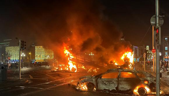 Las llamas se elevan desde el automóvil y el autobús, incendiados en el cruce de Bachelors Walk y el puente O'Connell, en Dublín, el 23 de noviembre de 2023. (Foto de Peter MURPHY / AFP)