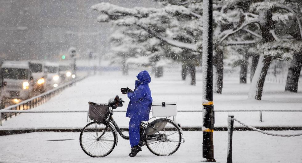 Una persona monta bicicleta en una calle cubierta de nieve en Tokio, Japón, el 6 de enero de 2022. (Behrouz MEHRI / AFP).