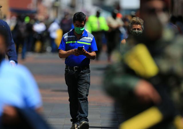 Ciudadanos ecuatorianos transitan con mascarillas por las calles de Quito. (EFE/José Jácome).
