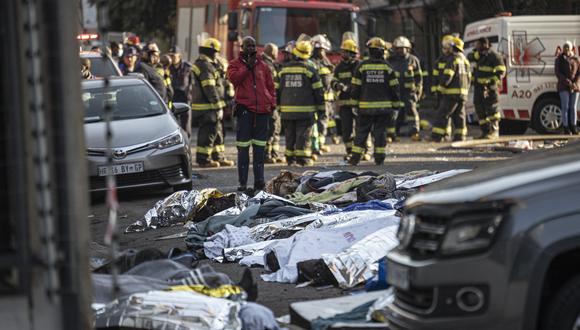 Se ven cuerpos cubiertos con mantas y sábanas en la escena de un incendio en Johannesburgo el 31 de agosto de 2023. (Foto: Michele Spatari / AFP)